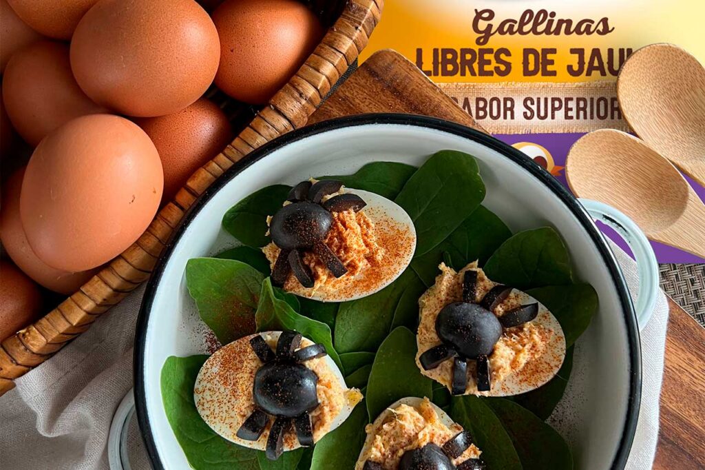 Una fotografía de un desayuno creativo para niños que consiste en huevos rellenos decorados como arañas