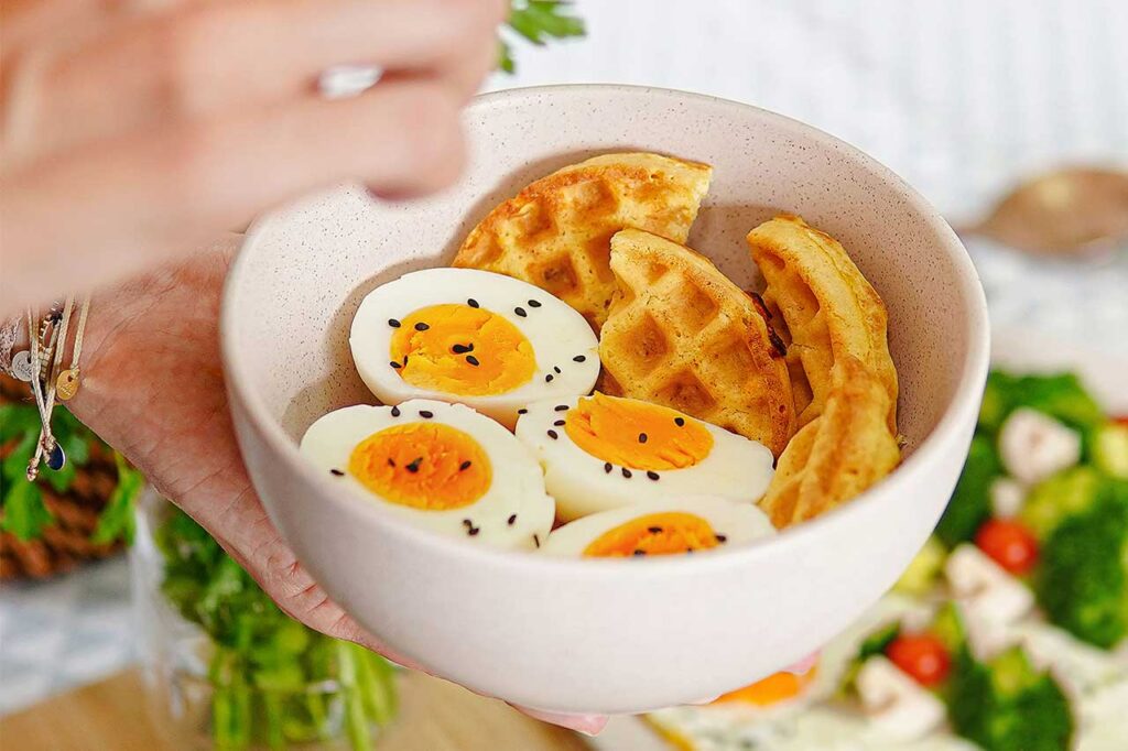 Desayuno saludable compuesto por huevos cocidos ricos en proteína y waffles, presentado en un bowl