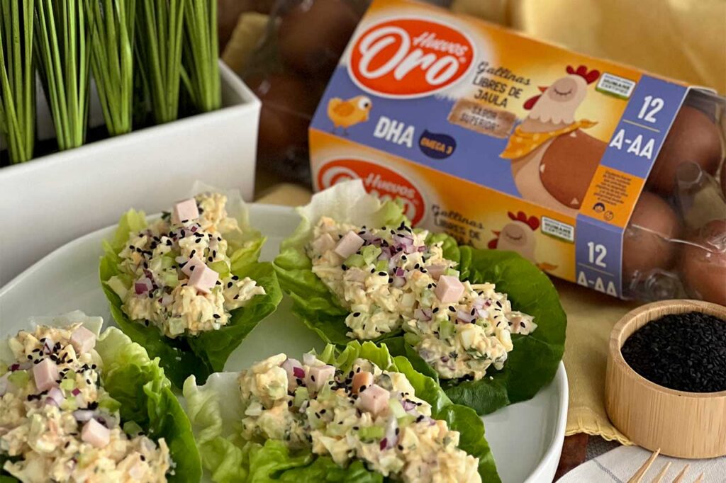 Cuatro wraps de lechuga rellenos con ensalada de huevo y jamón picado, espolvoreados con semillas de sésamo negro.
