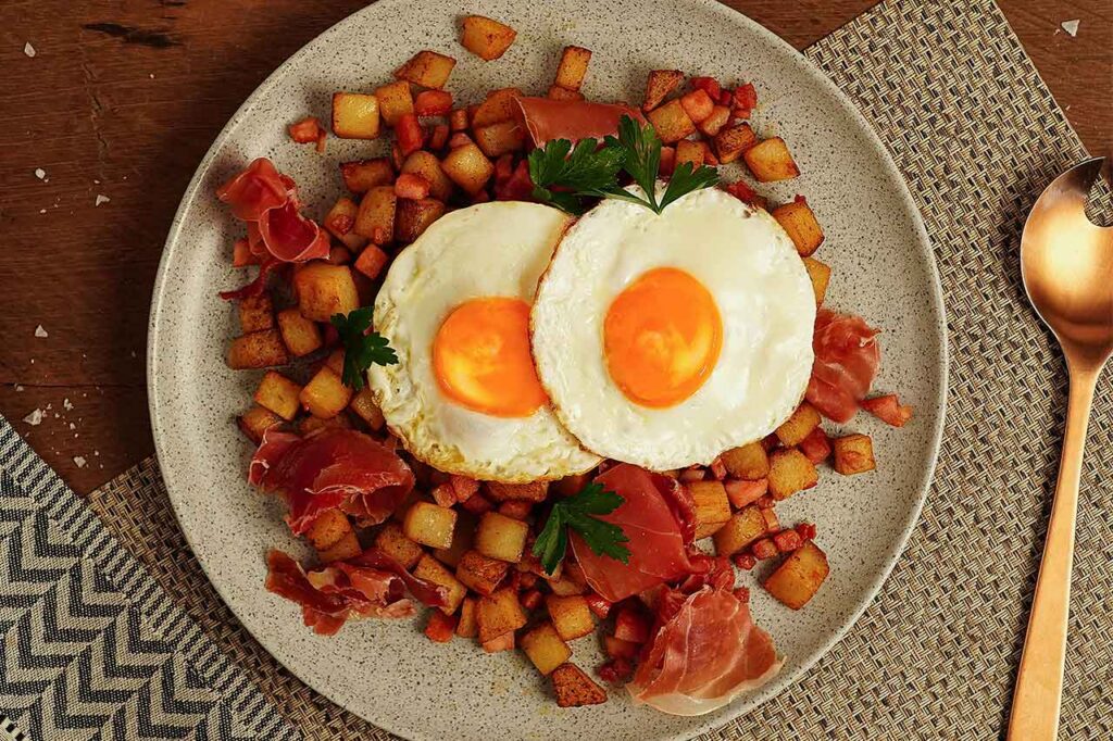Plato de huevos fritos con papa y jamón, una opción de desayuno o comida tradicional alta en proteínas