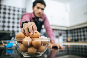 Un hombre cocinando huevos con seguridad alimentaria.