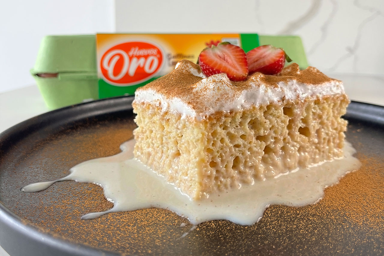 Porción de torta de tres leches húmeda y esponjosa con crema batida, canela y fresas