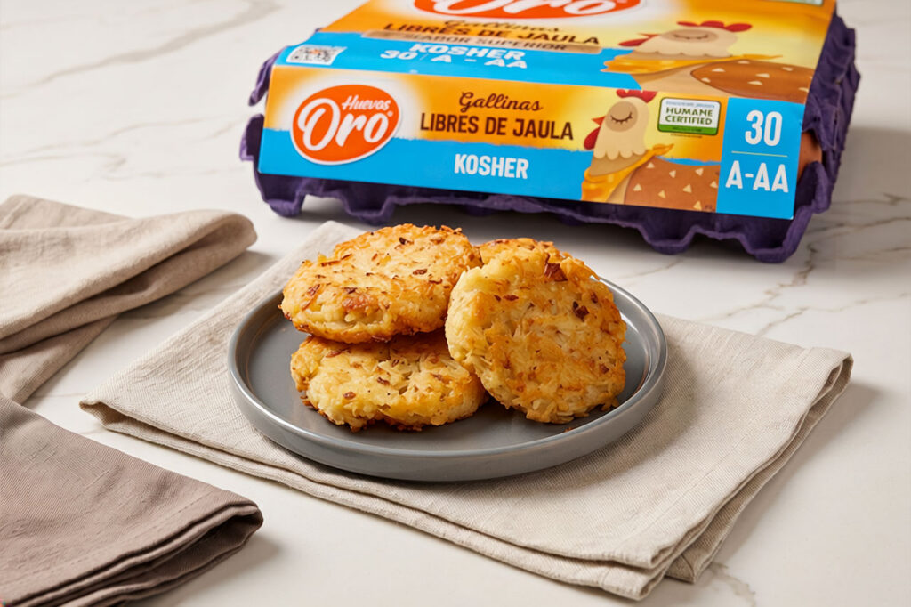 Tortitas de papa rallada o hash browns doradas y crujientes sobre un plato gris, con un empaque de Huevos Oro al fondo