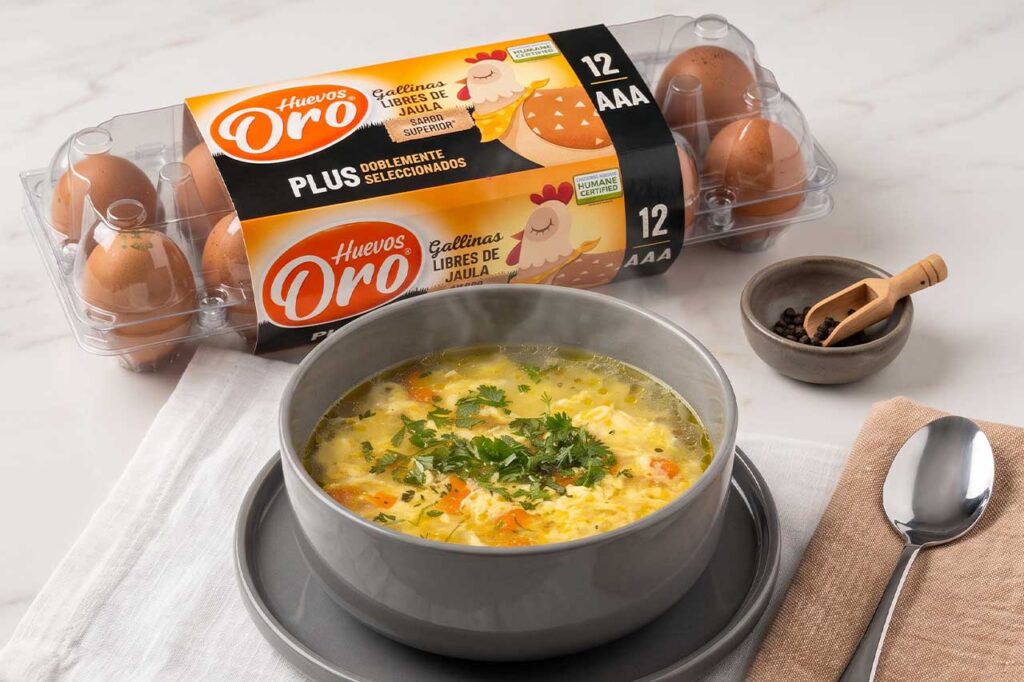 Plato de sopa casera humeante con verduras y huevo
