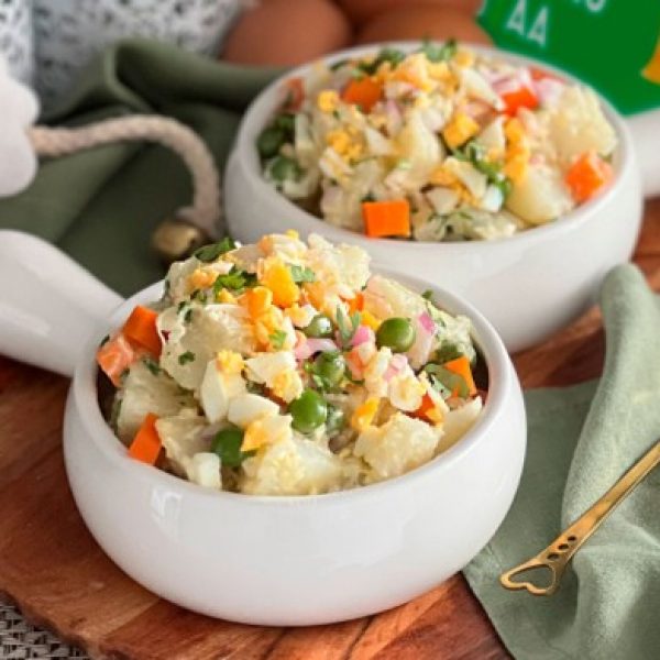 Ensalada con huevo y papa servida en plato blanco.
