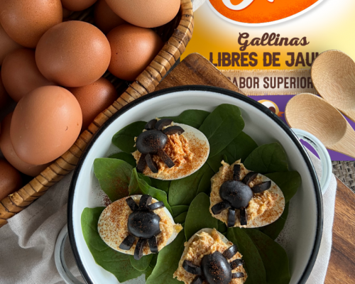 Huevos rellenos decorados con aceitunas sobre espinaca